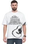 Male model wearing a white oversized T-shirt featuring “My Soul Speaks in Six Strings” typography and a black-and-white acoustic guitar graphic, paired with dark jeans and a black watch.