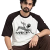 Male model wearing a loose cream and dark raglan T-shirt featuring a classical figure and “INSPIRATION” graphic