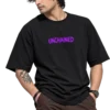 Clean-shaven male model wearing an oversized black T-shirt with bold purple “UNCHAINED” lettering