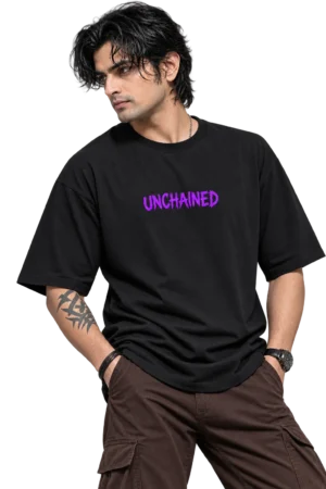 Clean-shaven male model wearing an oversized black T-shirt with bold purple “UNCHAINED” lettering