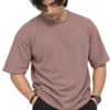 Male fashion model wearing a loose dusty mauve oversized T-shirt with curly black hair and dark cargo pants