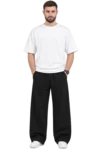Indian male model wearing relaxed black wide-leg pants with an elastic drawstring waist, paired with a white oversized T-shirt and white sneakers.