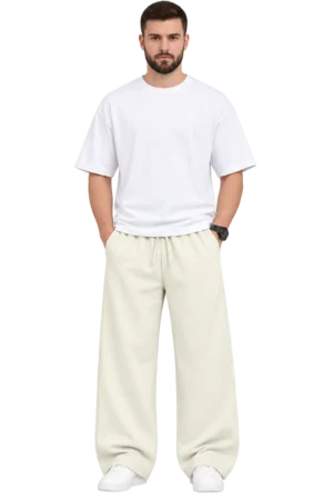 Male model wearing cream-colored wide-leg relaxed fit pants with an elastic drawstring waist, styled with a white oversized T-shirt and white sneakers.