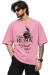 Male fashion model wearing a dusty pink oversized T-shirt featuring a gothic skull, raven, books and the quote “When Reason Fails, the Devil helps!