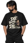 Die Before You Die – Graphic T-Shirt Model Male model wearing an oversized black T-shirt featuring a bold cream “Die Before You Die” graphic with a thoughtful cartoon character.