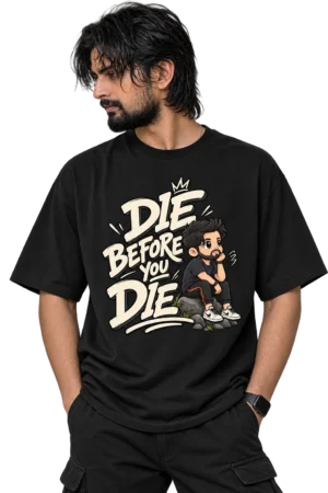 Male model wearing an oversized black T-shirt featuring a bold cream “Die Before You Die” graphic with a thoughtful cartoon character.